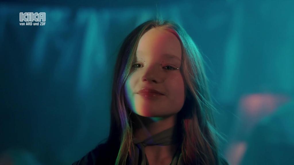 Marianna Kłos lächelt in die Kamera, um sie herum dunkelblaues Licht.