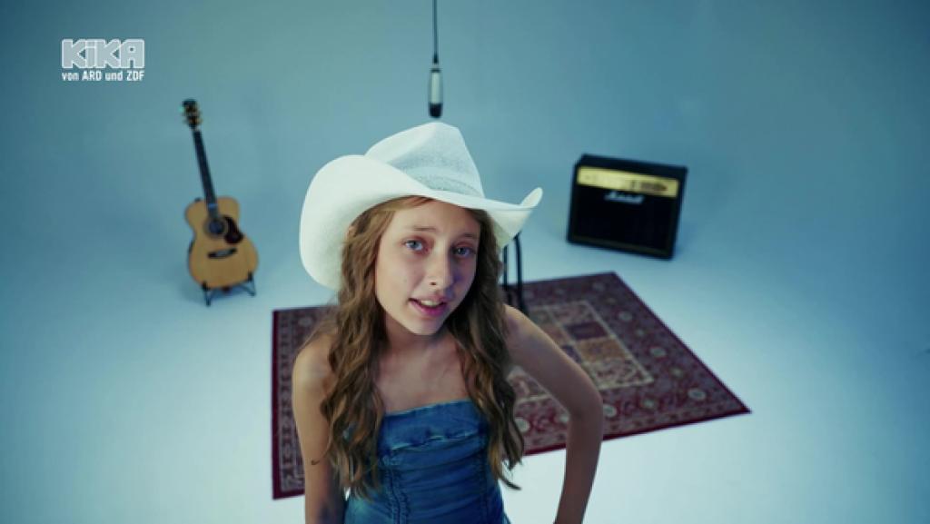 Martina CRV trägt einen Cowboyhut. Im Hintergrund steht ihre Gitarre.