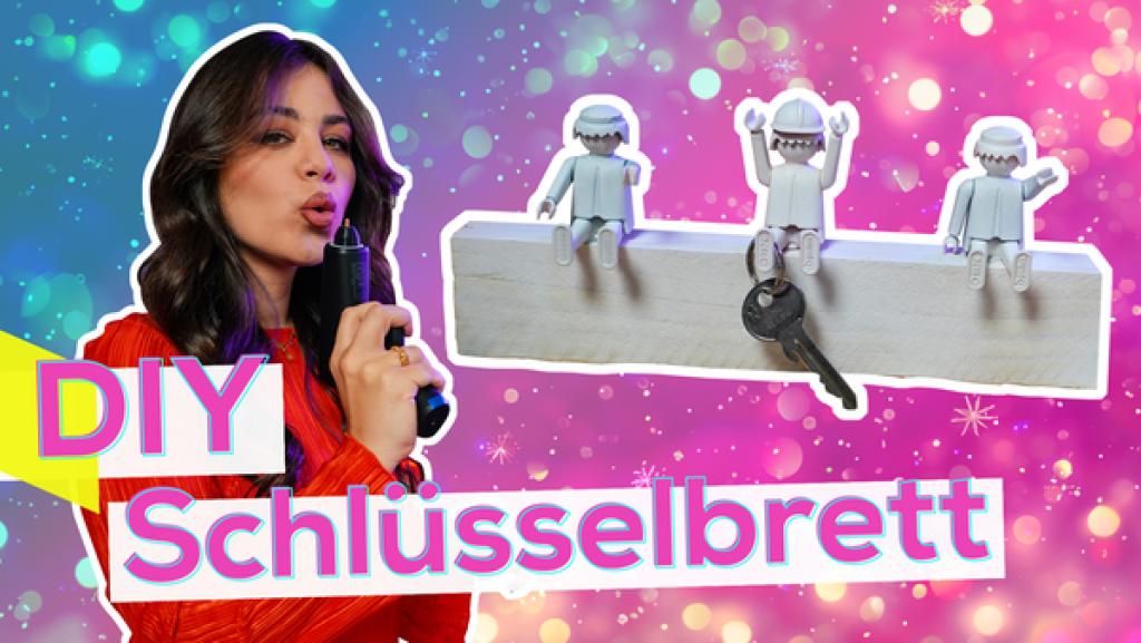 DIY Schlüsselhalter | Rechte: KiKA / Torben Hagenau Sarah mit Heißklebepistole. Neben ihr Bild von einem Brett mit Figuren mit weißer Umrandung. Aufschrift: DIY Schlüsselbrett