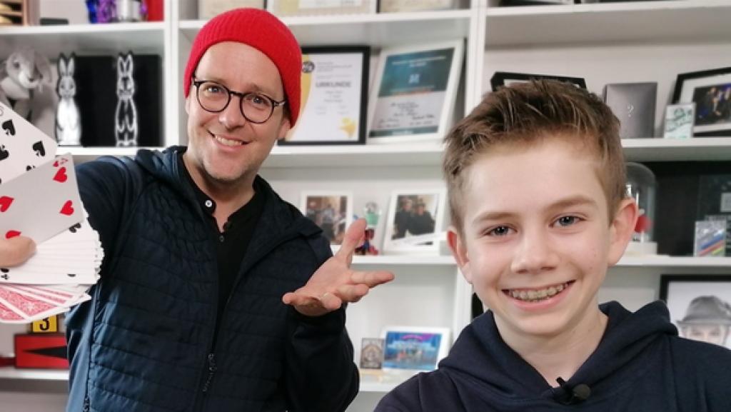 Ben steht links, rechts neben ihm Max. Beide halten ein ausgebreitetes Kartendeck in ihrer Hand und präsentieren es in die Kamera.