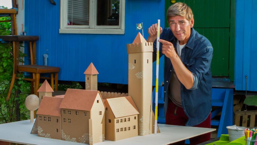 Fritz Fuchs steht vor dem Bauwagen mit einem Metermaß in der Hand