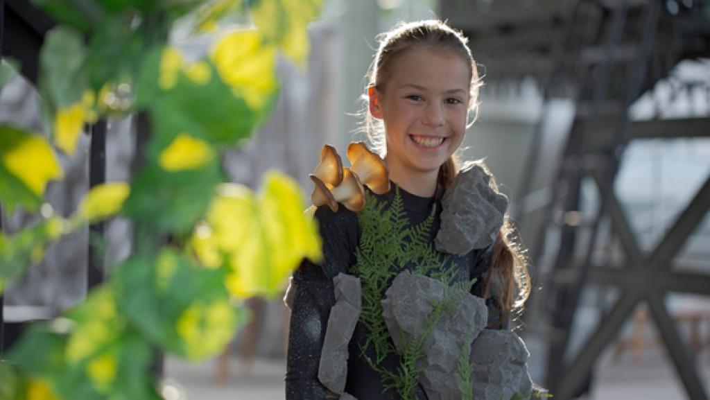 Rechte: MDR/Sebastian Jacobi Ida steht lächelnd im Sonnenlicht und trägt ein Gnom Küstüm. Das besteht aus einem grauen langärmeligen Top, an dem Pilze und Steine aus Schaumstoff befestigt sind.