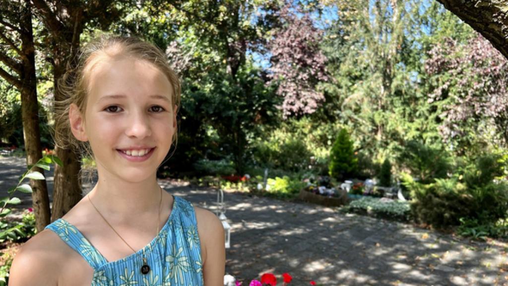 Rechte: rbb/Silke Cölln Das Mädchen Mathilda steht im linken Bildbereich. Im Hintergrund sind ein Schotterweg und grüne Bäume zu sehen. Ein Friedhof.