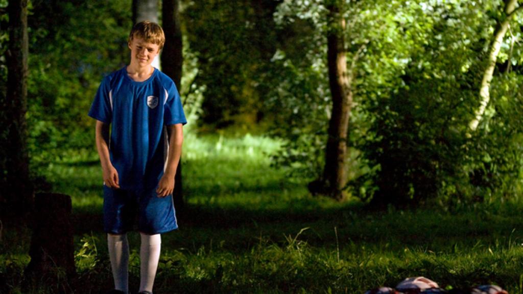 Junge mit Fußballsachen im Wald.