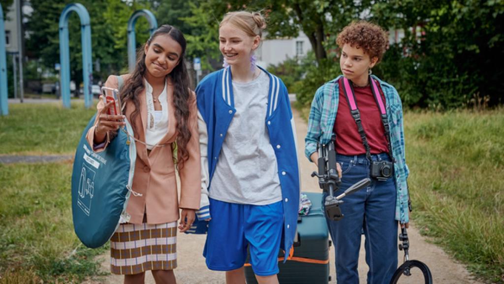 Schloss Einstein (1032) | Rechte: Kika Drei Mädchen schauen vergnügt auf ein Mobiltelefon.