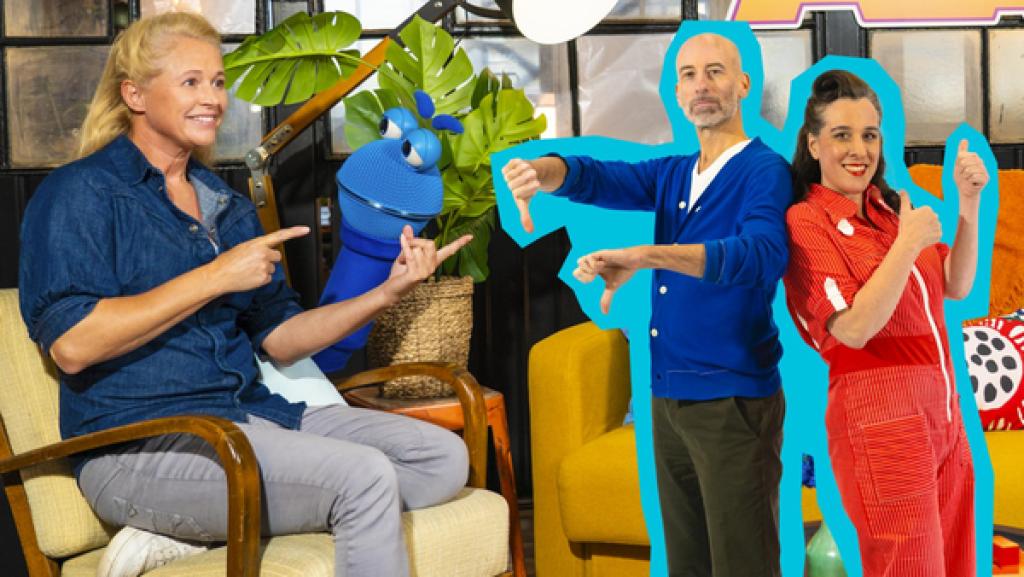 Singa sitzt auf einem Sessel und zeigt auf Lisa und Boris von der Band Eule und Lerche. Das SingDing schaut hinter dem Sessel hervor und guckt Singa freundlich an. Lisa und Boris stehen daneben; Lisa streckt die Daumen nach oben und Boris zeigt mit den Daumen nach unten.