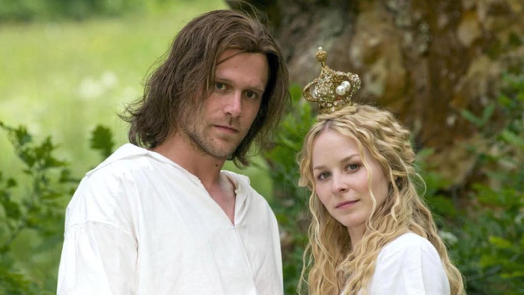 König Drosselbart | Rechte: hr/Jacqueline Krause-Burberg Prinz Richard alias König Drosselbart trägt ein weißes Hemd und Schulterlange brunettfarbene Haare. Prinzessin Isabella steht Schulter an Schulter dicht neben ihn, hat den Kopf leicht geneigt und schaut stolz. Sie hat lange blonde leicht gelockte Haare und trägt eine kleine goldene Krone auf dem Kopf.