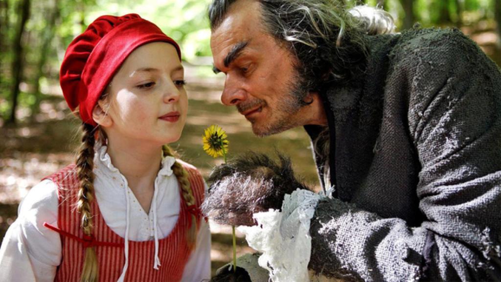 Rotkäppchen | Rechte: hr/Felix Holland Ein junges Mädchen mit roter Haube, aus denen ihre langen Zöpfe hervorschauen, schnuppert zusammen mit dem Wolf an einer Blume.