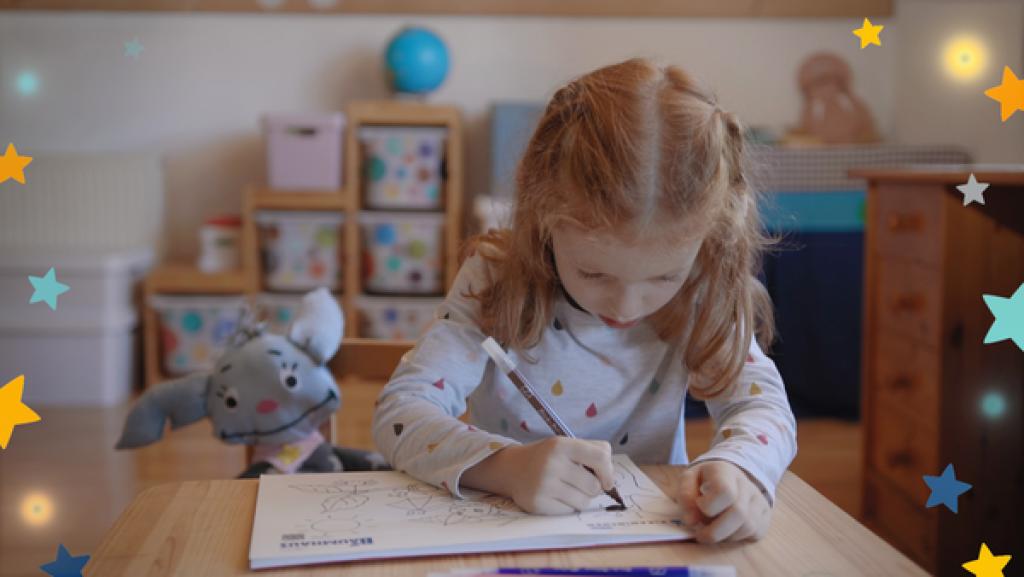 Ein blondes Mädchen an einem Tisch malt Ausmalbilder von Fidi 