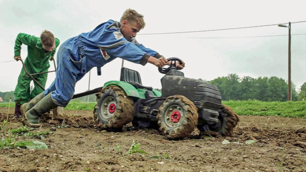 Leon und Jan pflügen das Feld mit ihrem Kindertraktor
