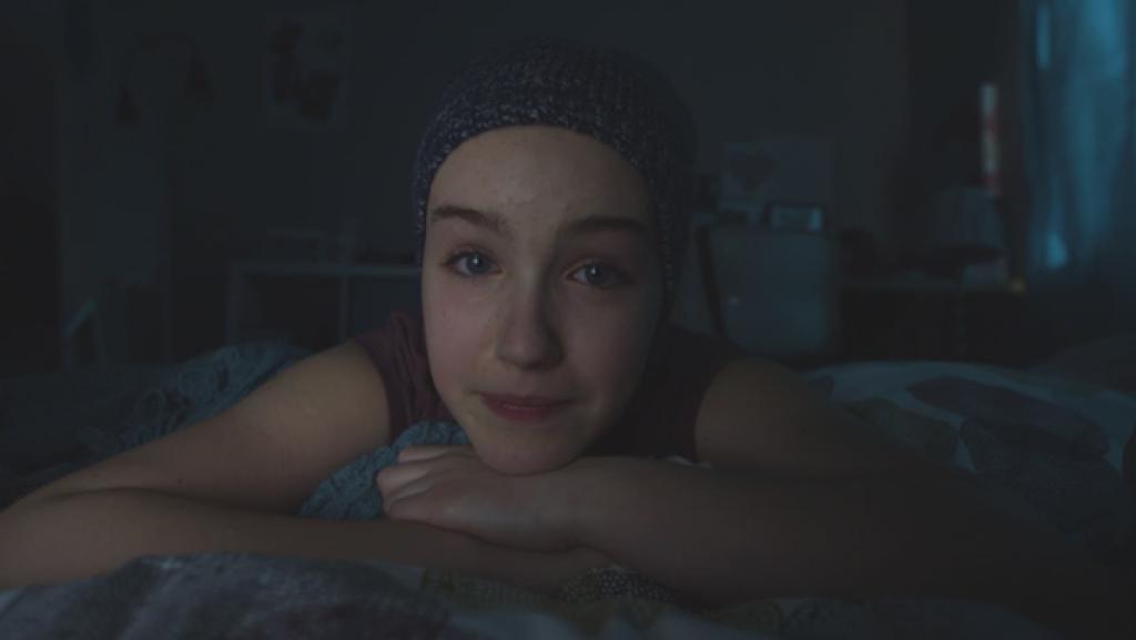 Jenny liegt in ihrem dunklen Zimmer auf dem Bett.