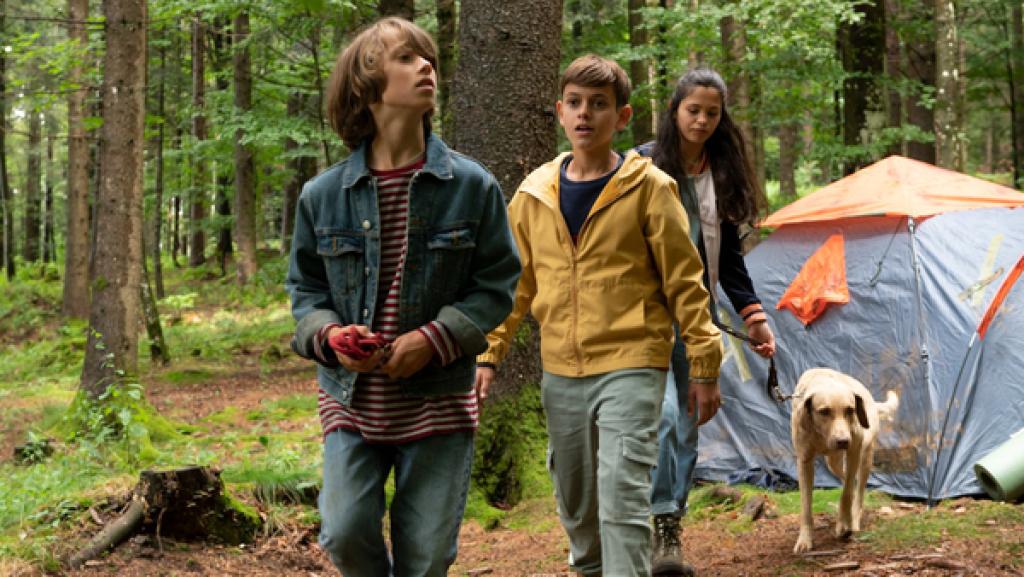 Drei Kinder mit Hund zelten im Wald