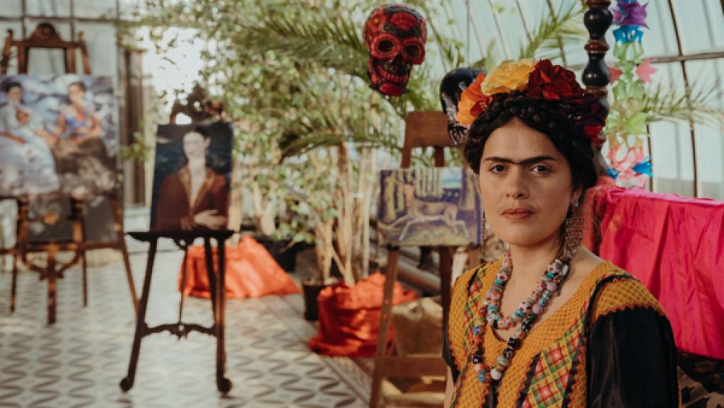 Rechte: KiKA/Sabine Finger Die mexikanische Malerin Frida Kahlo (Mina Sagdic) bei ihrer Vernissage. Im Hintergrund sind Gemälde von ihr zu sehen.