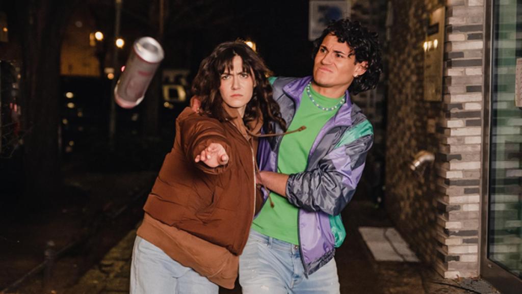 Young Crime - Staffel 2 - Im Streit ausgetickt | Rechte: ZDF Ein Mädchen mit dunklen Haaren und wütendem Gesichtsausdruck hat den Arm zum Wurf ausgestreckt. Vor ihr in der Luft fliegt eine Bierdose dem Betrachter des Bildes entgegen. Das Mädchen, das sie offenbar geworfen hat, wird von einem Jungen mit dunklen Locken und verkrampften Gesichtsausdruck festgehalten. Vorne links im Bild erkennt man noch einige Strähnen blondes Haar. Die drei Personen befinden sich draußen auf einem Bürgersteig, der von Straßenlaternen beleuchtet ist.