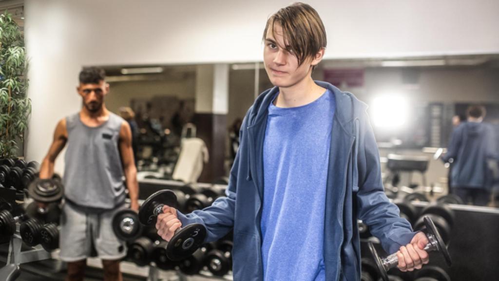 Young Crime - Staffel 2 - Pillen und Pumpen | Rechte: ZDF Im Hantelbereich eines Fitnessstudios stehen ein erwachsener durchtrainierter Mann, der gerade zwei Hanteln hebt, und ein schmaler blonder Junge, der zwei etwas leichtere Hanteln in den Händen hält. Beide blicken in die Kamera.